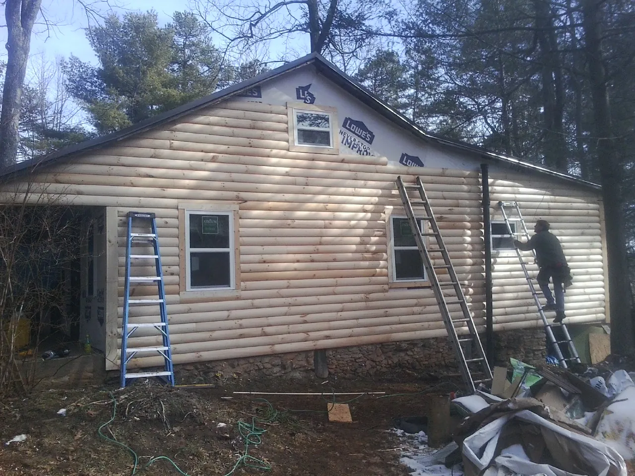 Ladders set against fresh log siding during an exterior remodel in Gulf