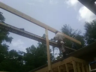 Carpenter setting a ridge beam over a new addition frame — Ice Dam Removal by Roofing Brothers in Gulf