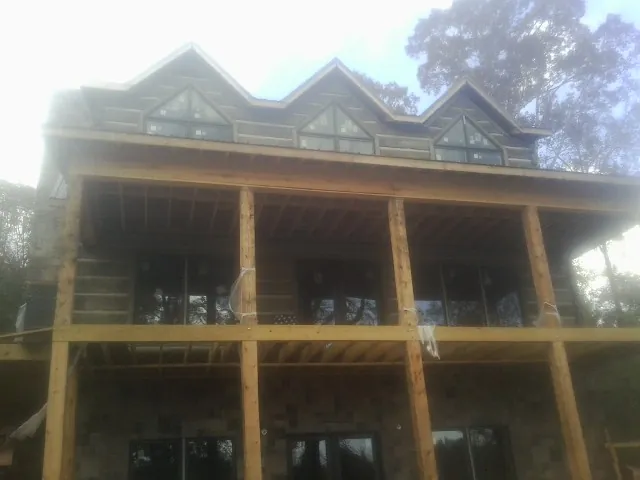 Dormers and porch framing on a large log home under construction — Roof Coating work by our crew in Gulf