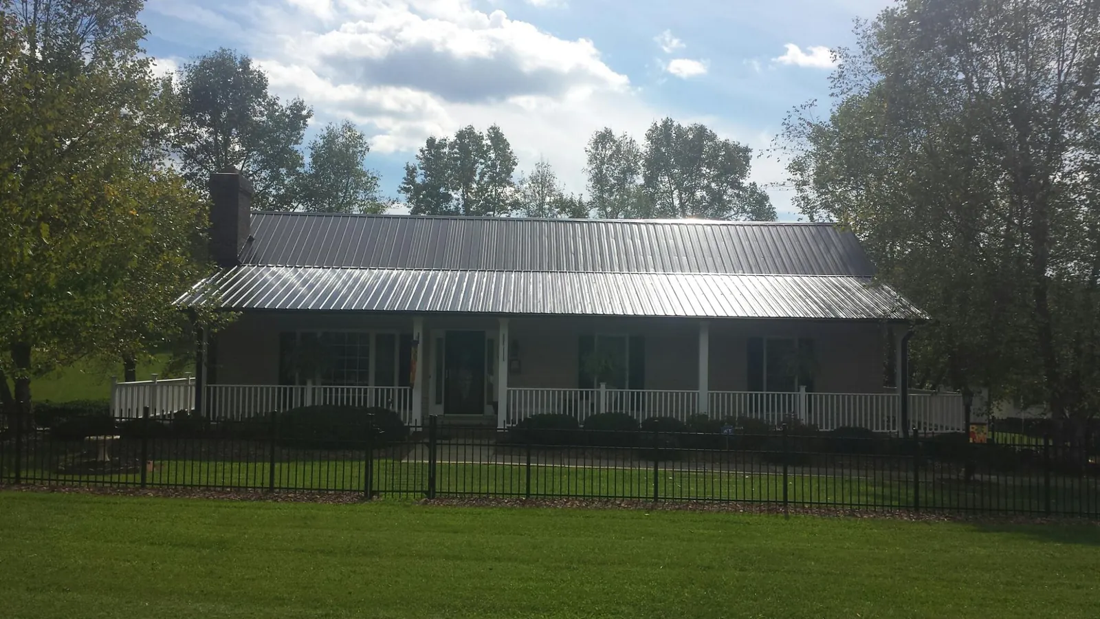 Gray metal roof on a brick ranch with a full width front porch — Gutter Guard Installation work by our crew in Gulf
