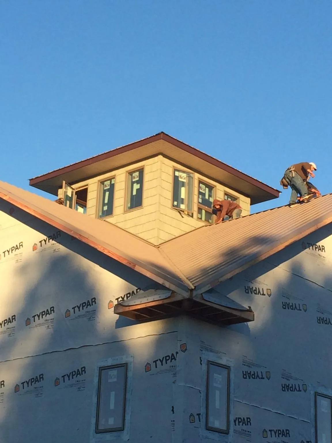 Roofers working around a rooftop cupola on a new metal roof at sunset — Roof Waterproofing in Gulf by Roofing Brothers